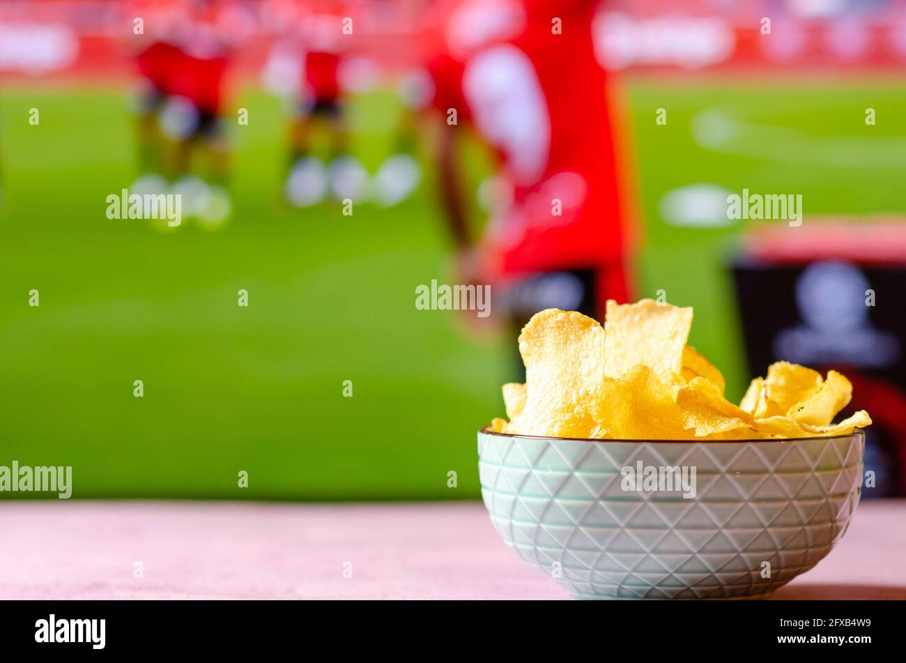 Ciotola di patatine per guardare il calcio. Snack con sfondo sportivo fuori fuoco. Foto Stock