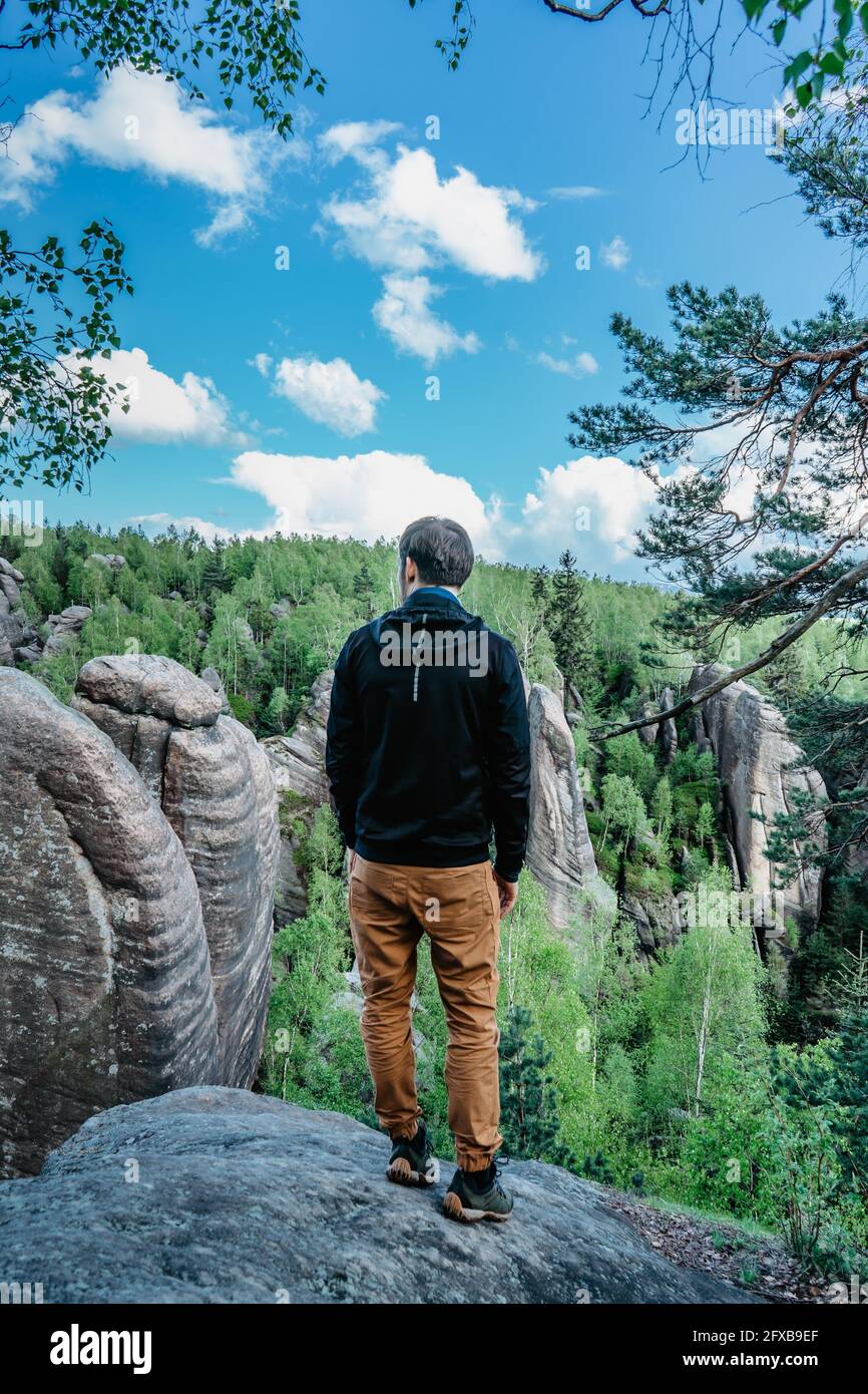 Viaggiatore maschile in piedi sulla roccia godendo di vedute della bizzarra arenaria Formazioni chiamate Broumovske steny, regione di Broumov, Repubblica Ceca.Wanderlust attivo Foto Stock