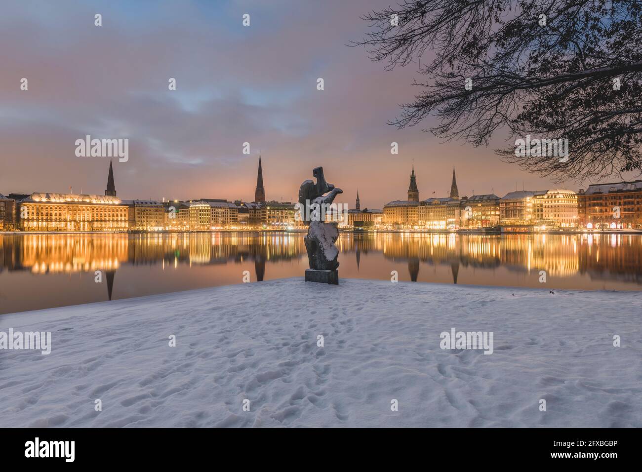 Germania, Amburgo, architettura cittadina illuminata che si riflette nel lago di Binnenalster al tramonto d'inverno Foto Stock