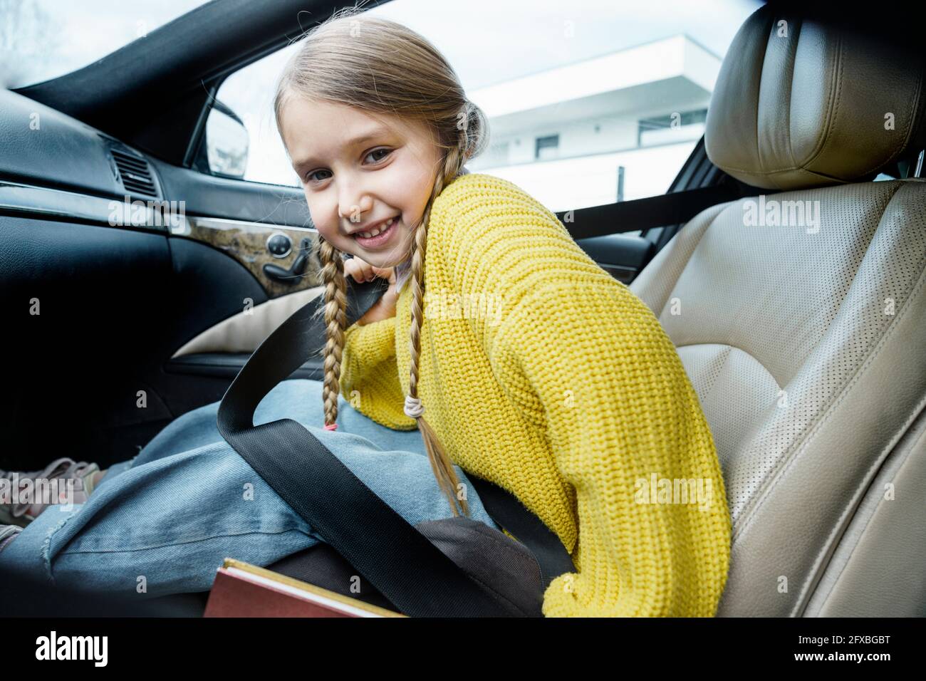 Sorridente ragazza carina che indossa trecce seduto in auto Foto Stock