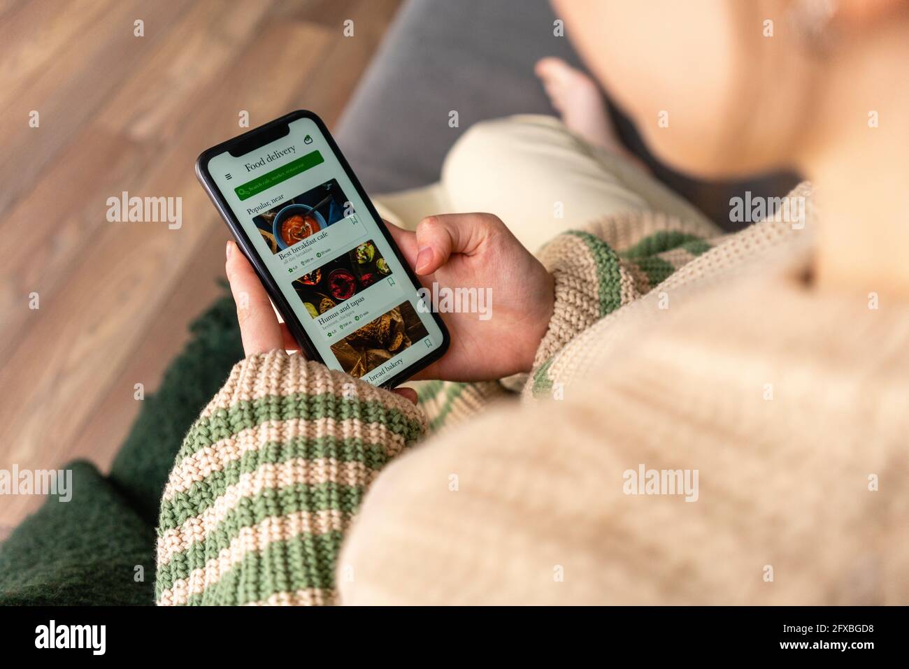 Giovane donna che ordina cibo sul telefono cellulare a casa Foto Stock