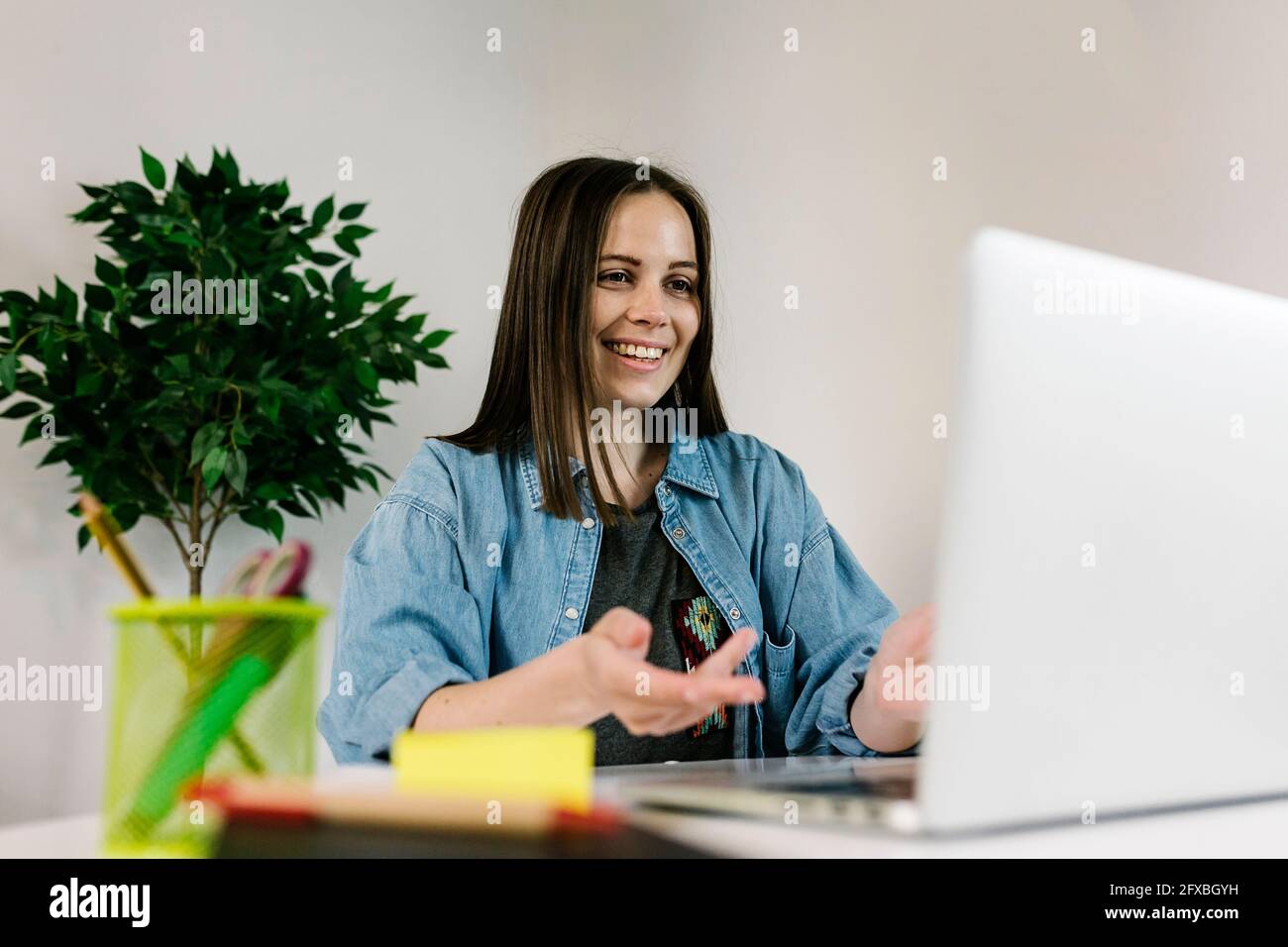 Sorridente imprenditore femminile che parla durante la videoconferenza attraverso il computer portatile a casa Foto Stock
