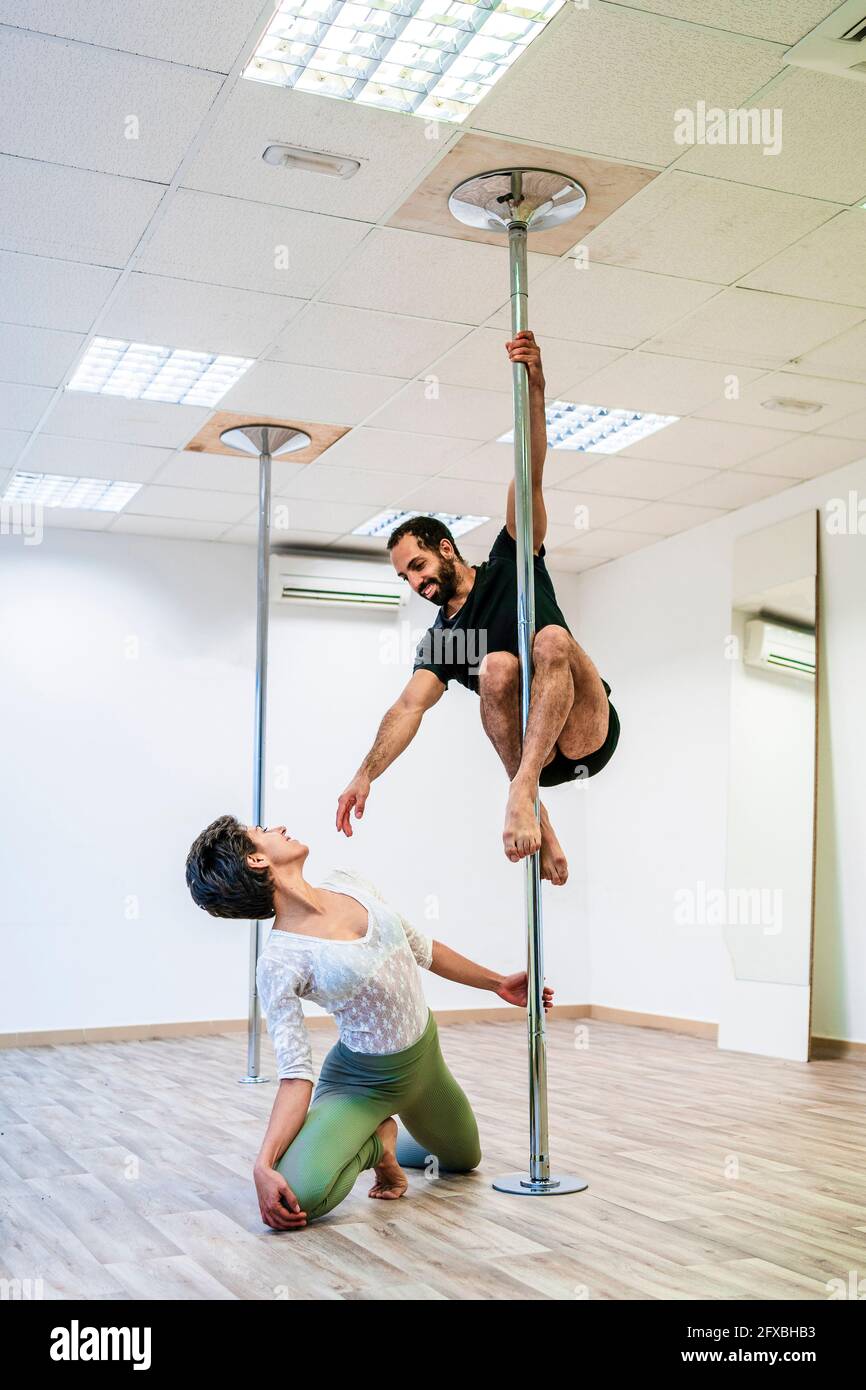 Ballerina femminile che guarda l'acrobat maschile che pratica su Rod in studio di danza Foto Stock