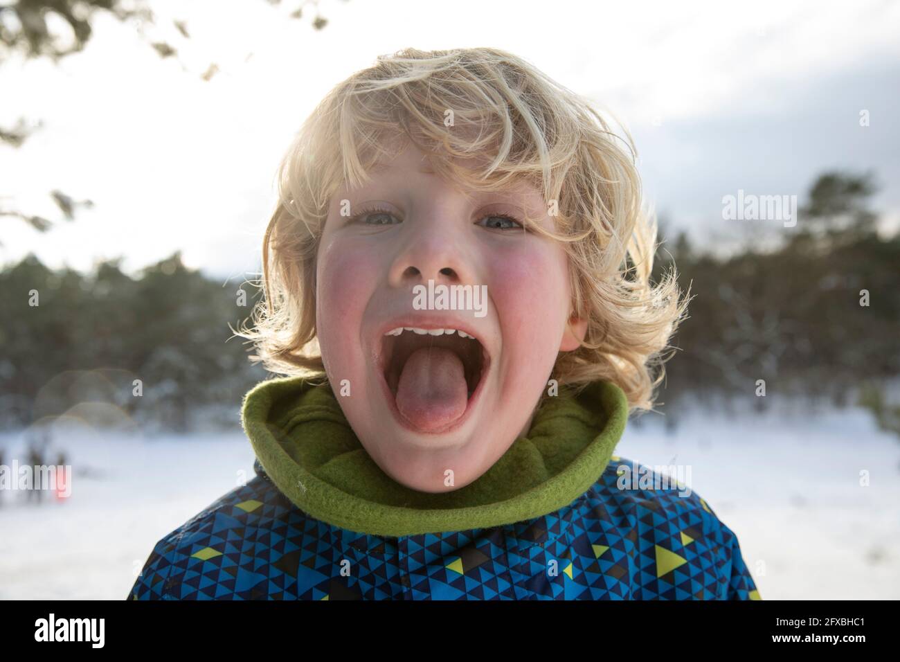 Ragazzo biondo che si stacca la lingua durante l'inverno Foto Stock