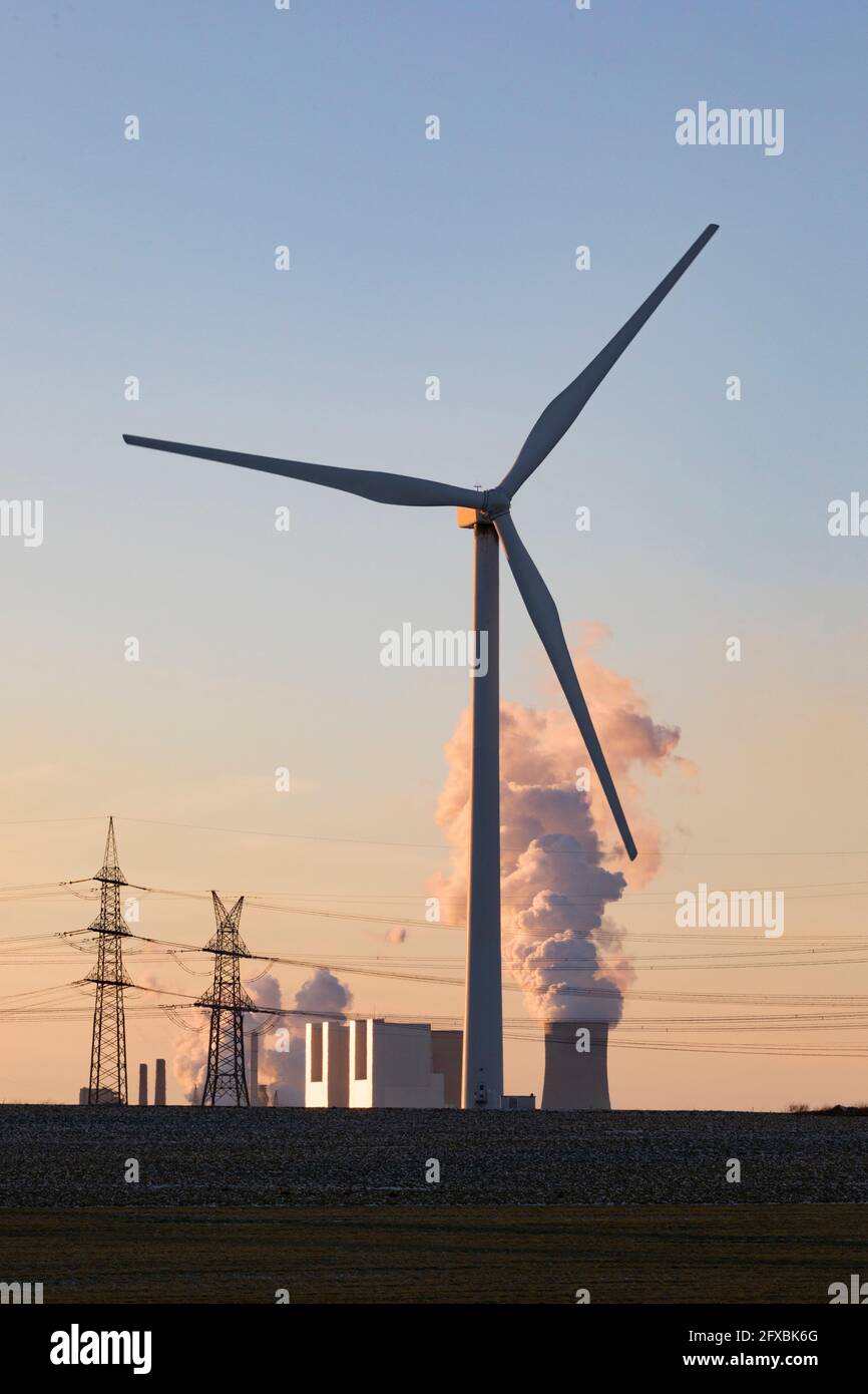 Germania, Renania Settentrionale Vestfalia, Grevenbroich, turbine eoliche e piloni elettrici al tramonto Foto Stock