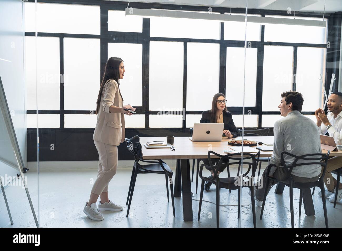 Professionisti di sesso maschile e femminile sorridenti durante la riunione visto attraverso il vetro in ufficio Foto Stock