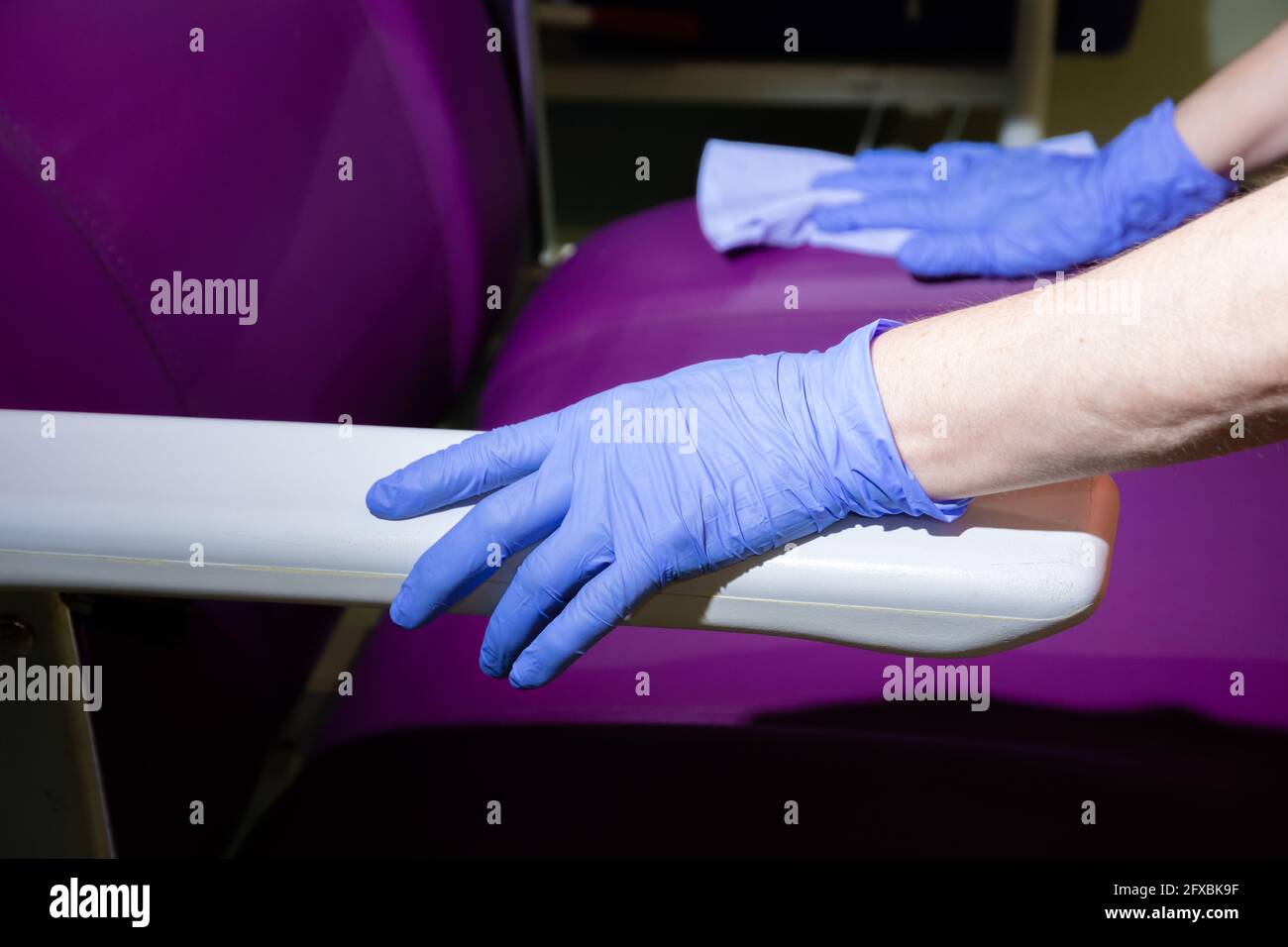 mani con un guanto e un panno blu che pulisce un sedia viola in un ospedale  Foto stock - Alamy