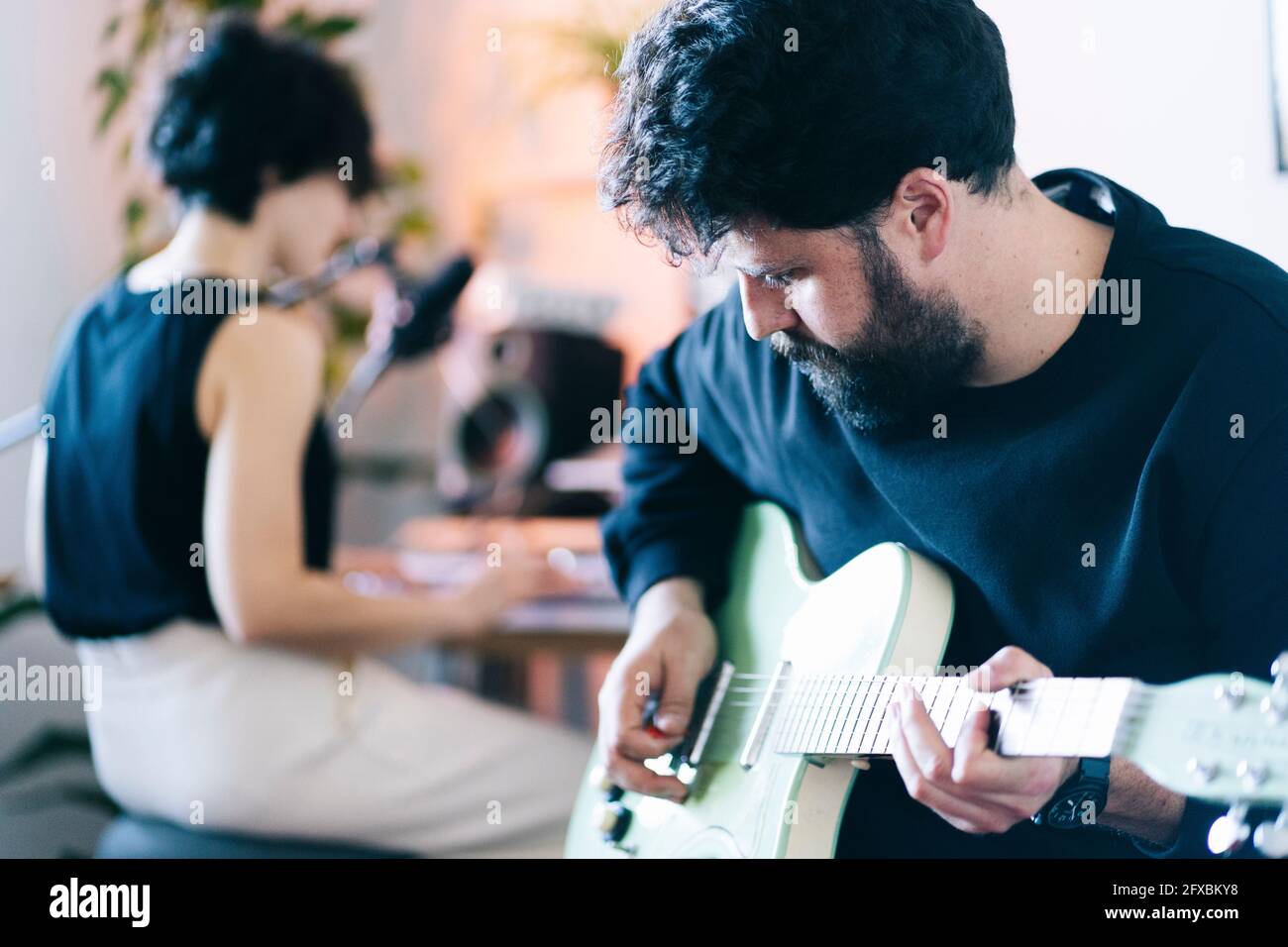 Compositore maschile che suona la chitarra in studio Foto Stock