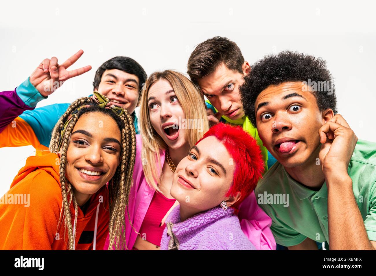 I giovani amici si divertano mentre fanno i volti su sfondo bianco Foto Stock