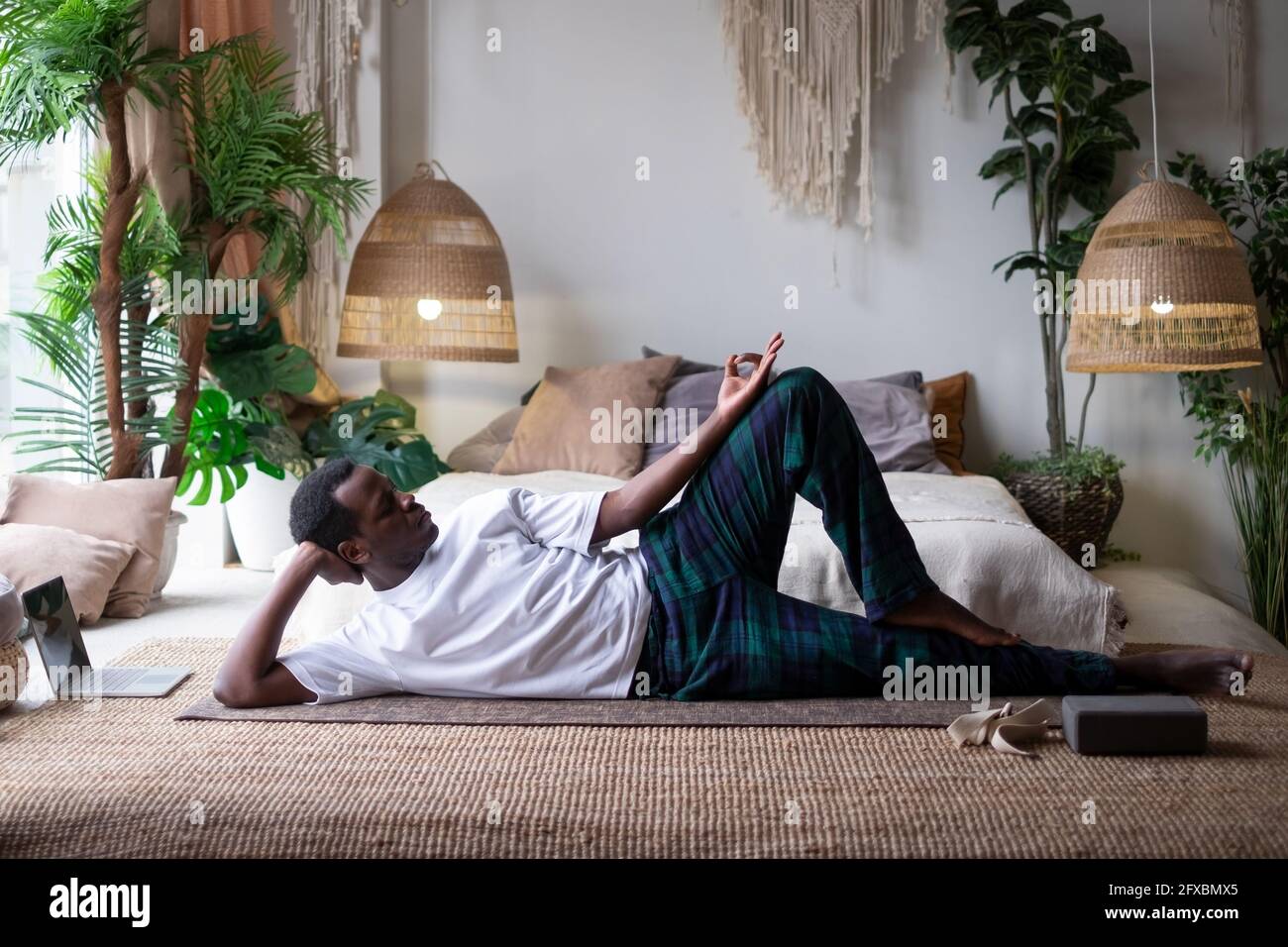 L'uomo africano di yoga che fa anantasana posa allenarsi a casa Foto Stock