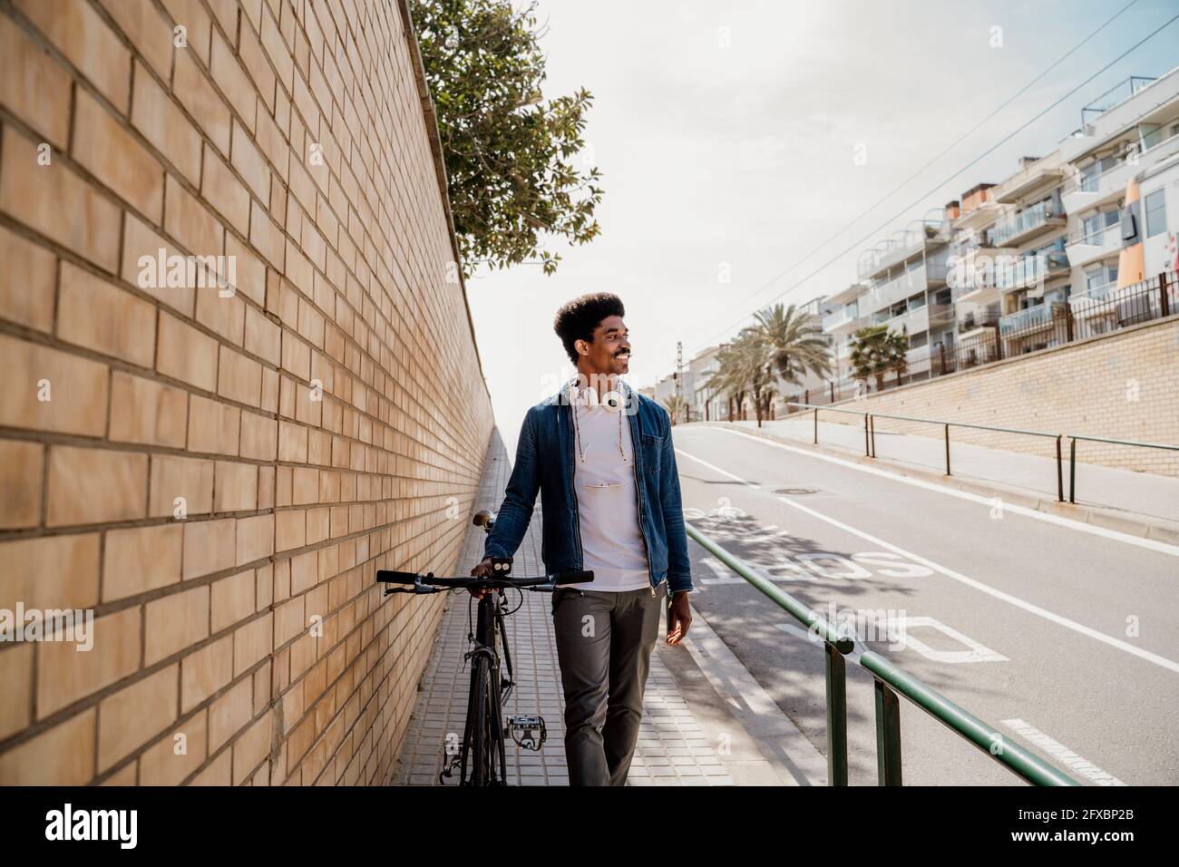 Sorridente bell'uomo che guarda via mentre cammina in bicicletta sul sentiero Foto Stock