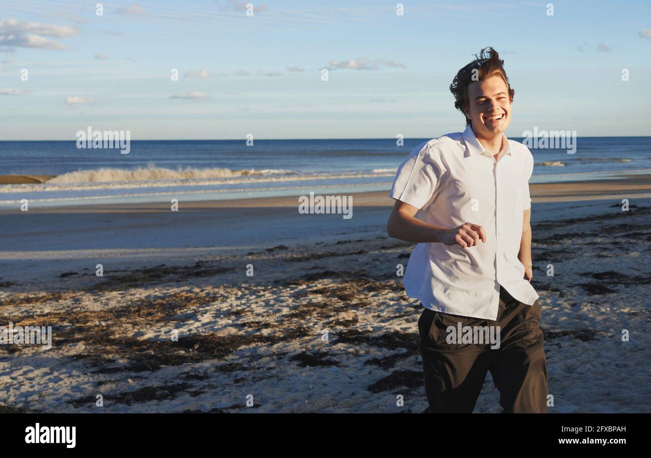 Sorridente giovane che corre sulla spiaggia Foto Stock