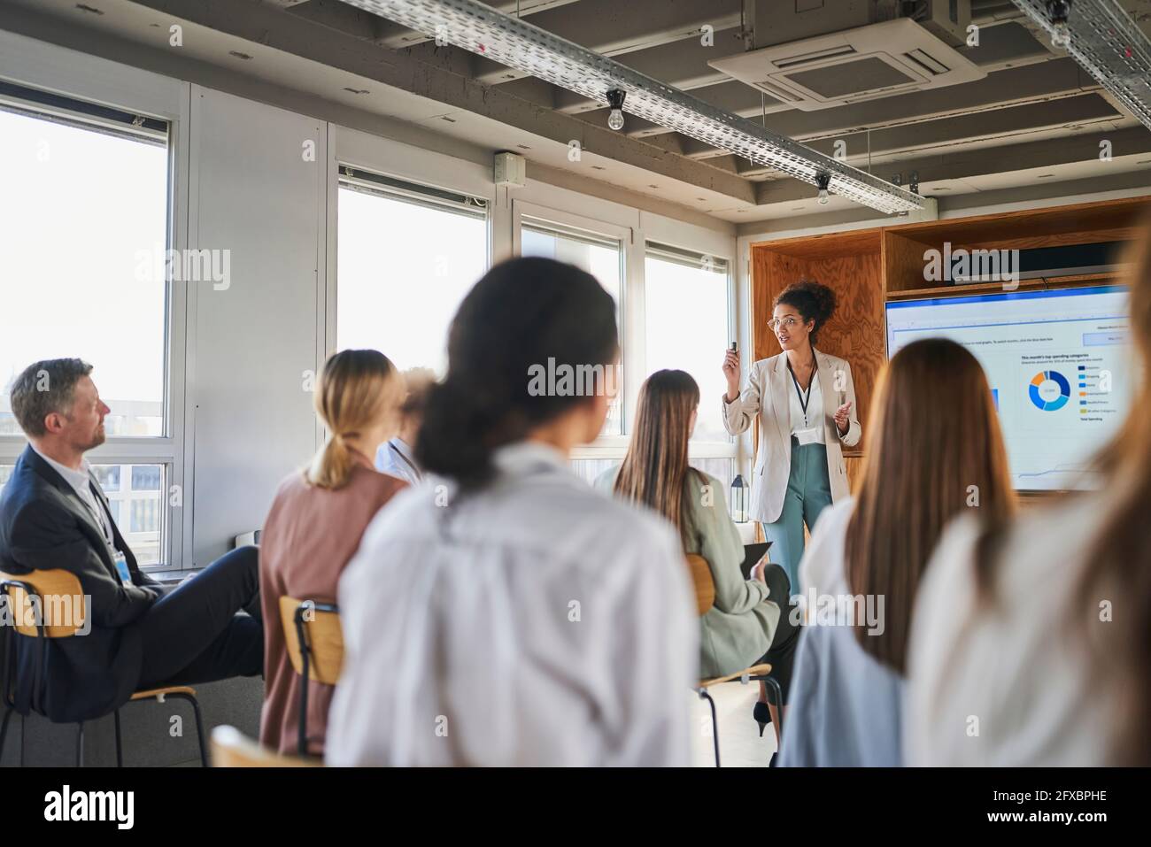 Donna d'affari che spiega il programma di affari ai colleghi in evento educativo Foto Stock
