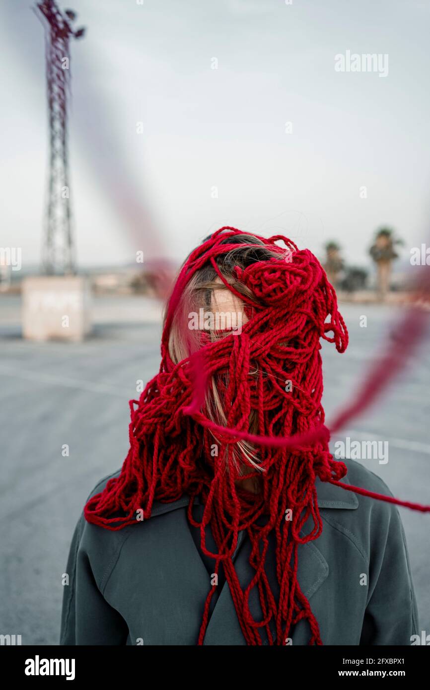 Donna che copre il viso con filo rosso sulla strada Foto Stock