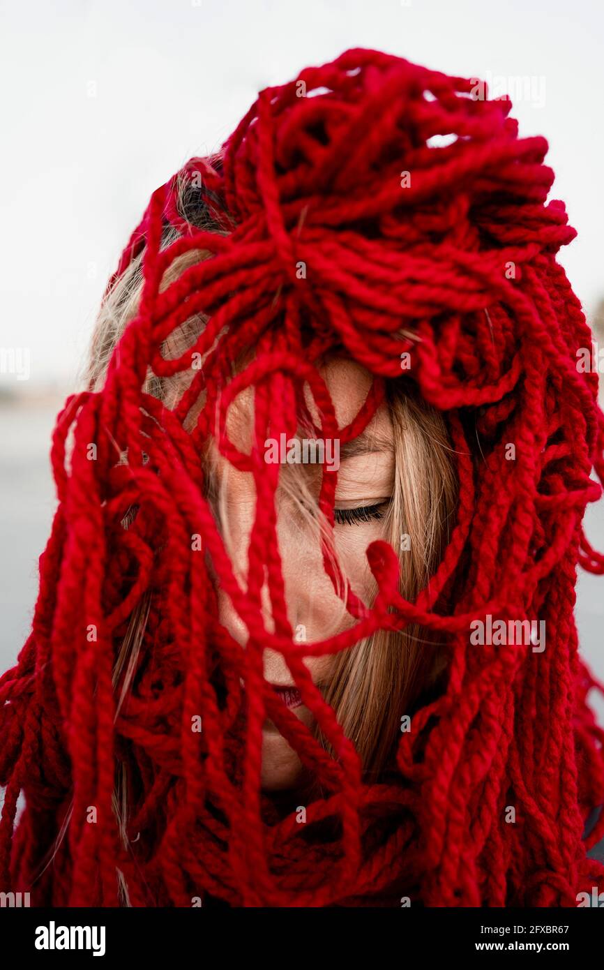 Donna che ricopre il viso con filo rosso Foto Stock