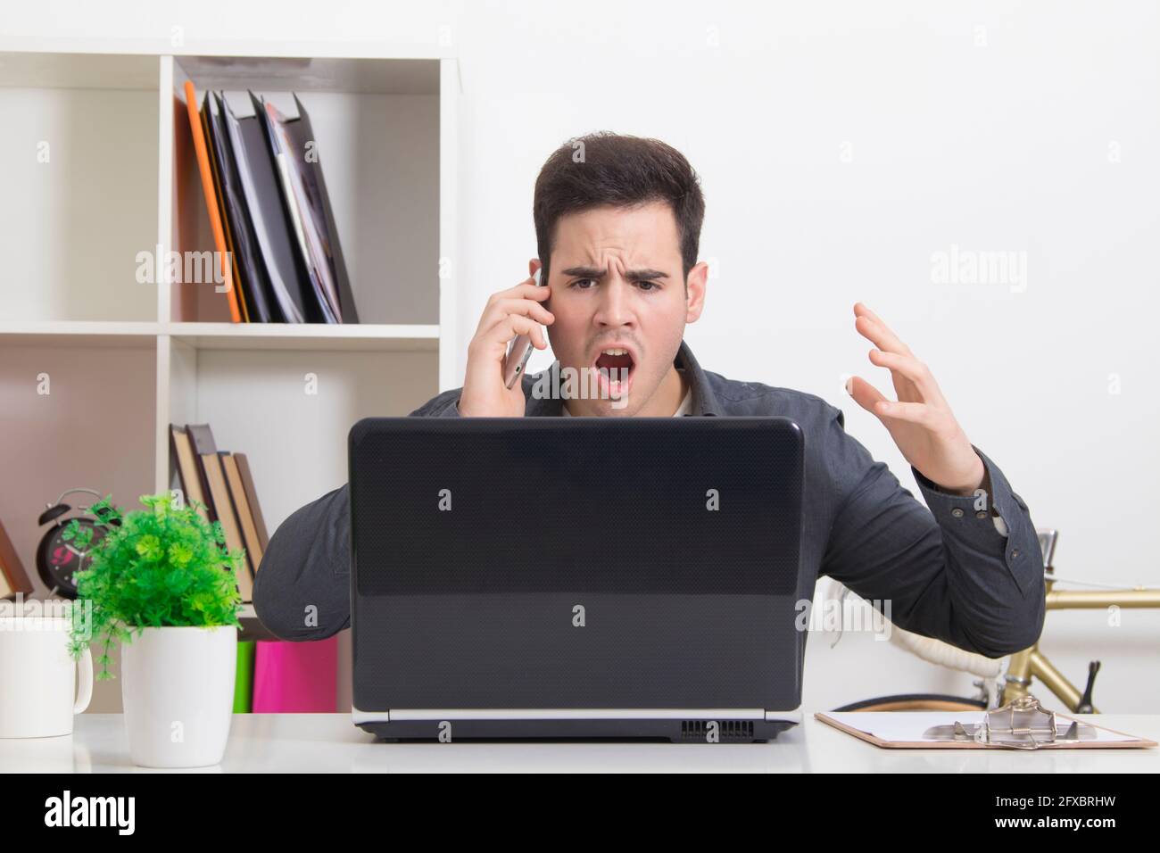 uomo arrabbiato e sconvolto piangendo dal telefono nel in ufficio o a casa Foto Stock