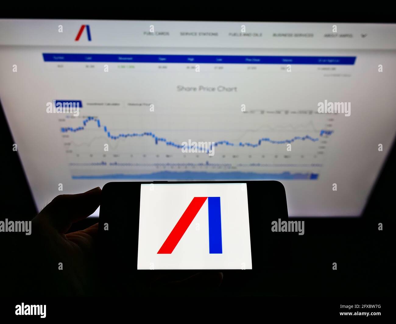 Persona che detiene smartphone con logo della società australiana di petrolio, carburante e gas Ampol Limited sullo schermo di fronte al sito web. Mettere a fuoco il display del telefono. Foto Stock