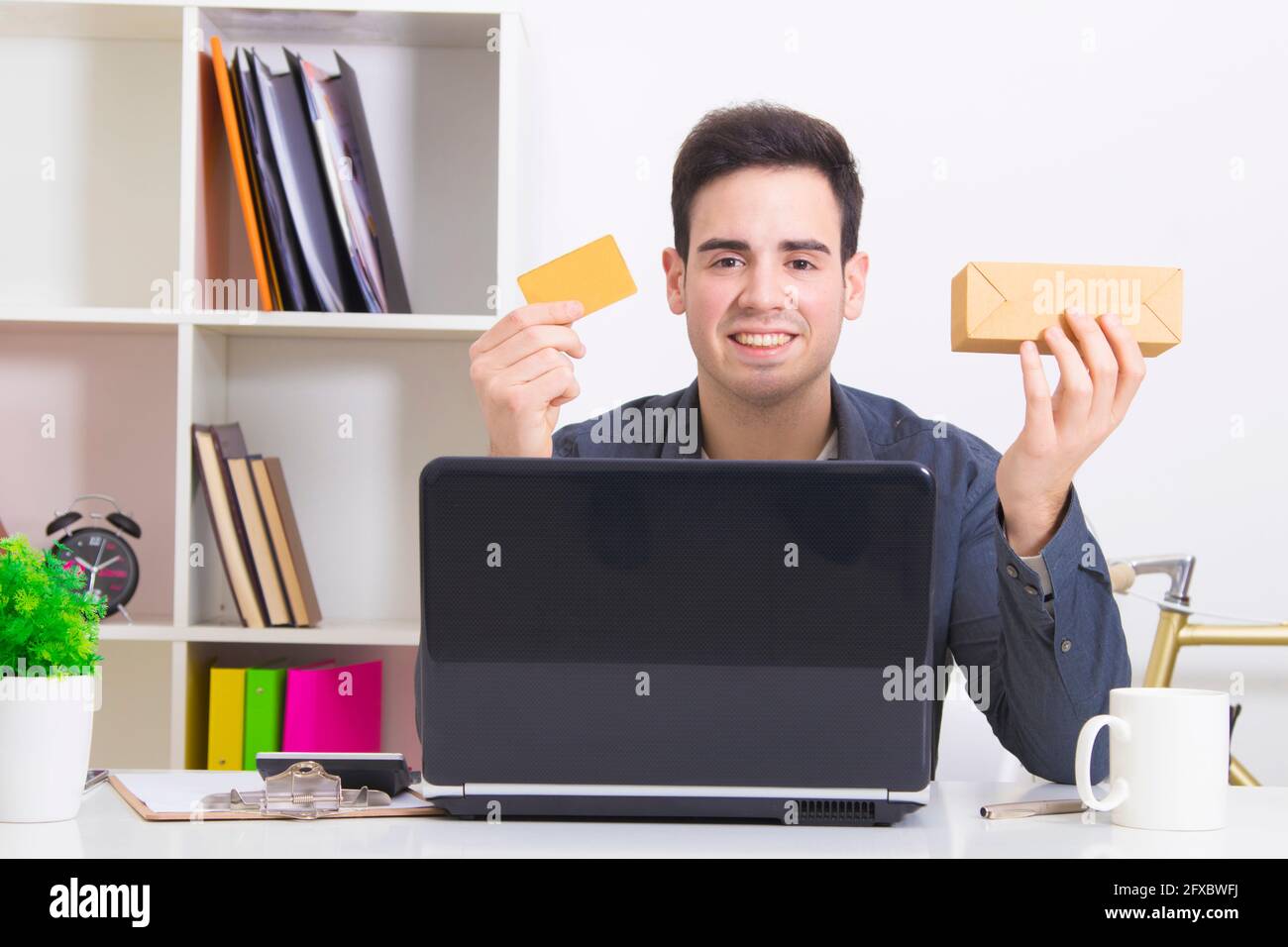 Uomo con carta di credito e computer laptop con box acquisti Foto Stock