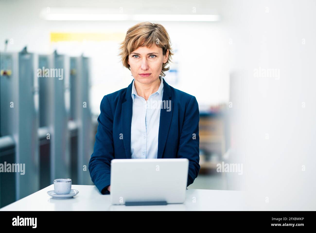 Donna d'affari premurosa con tablet digitale in fabbrica di stampa Foto Stock