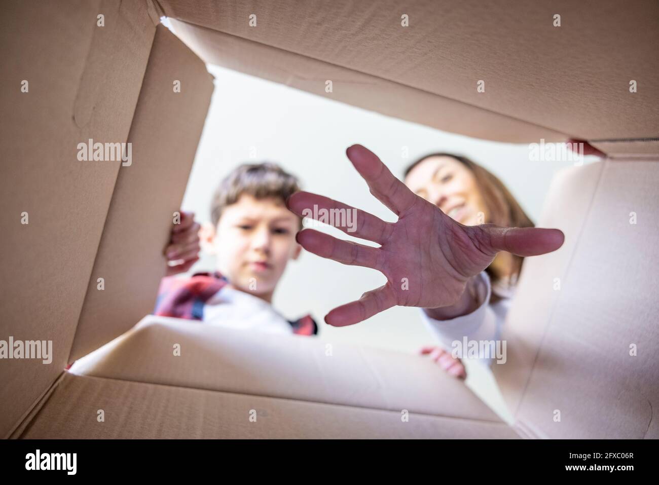 Madre che mette mano nella scatola di sorpresa da figlio Foto Stock