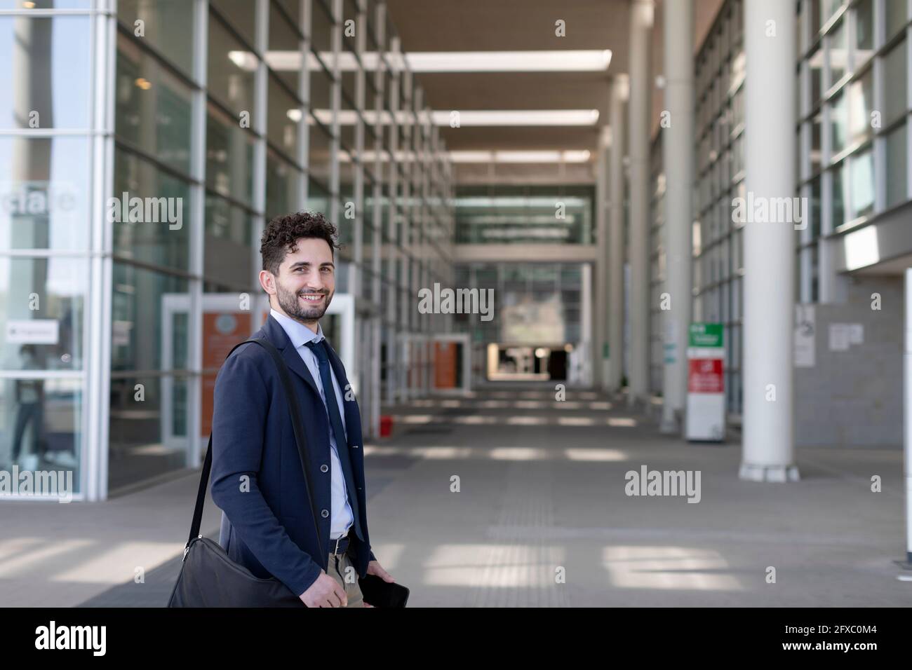 Sorridente professionista con borsa a spalla sul sentiero Foto Stock