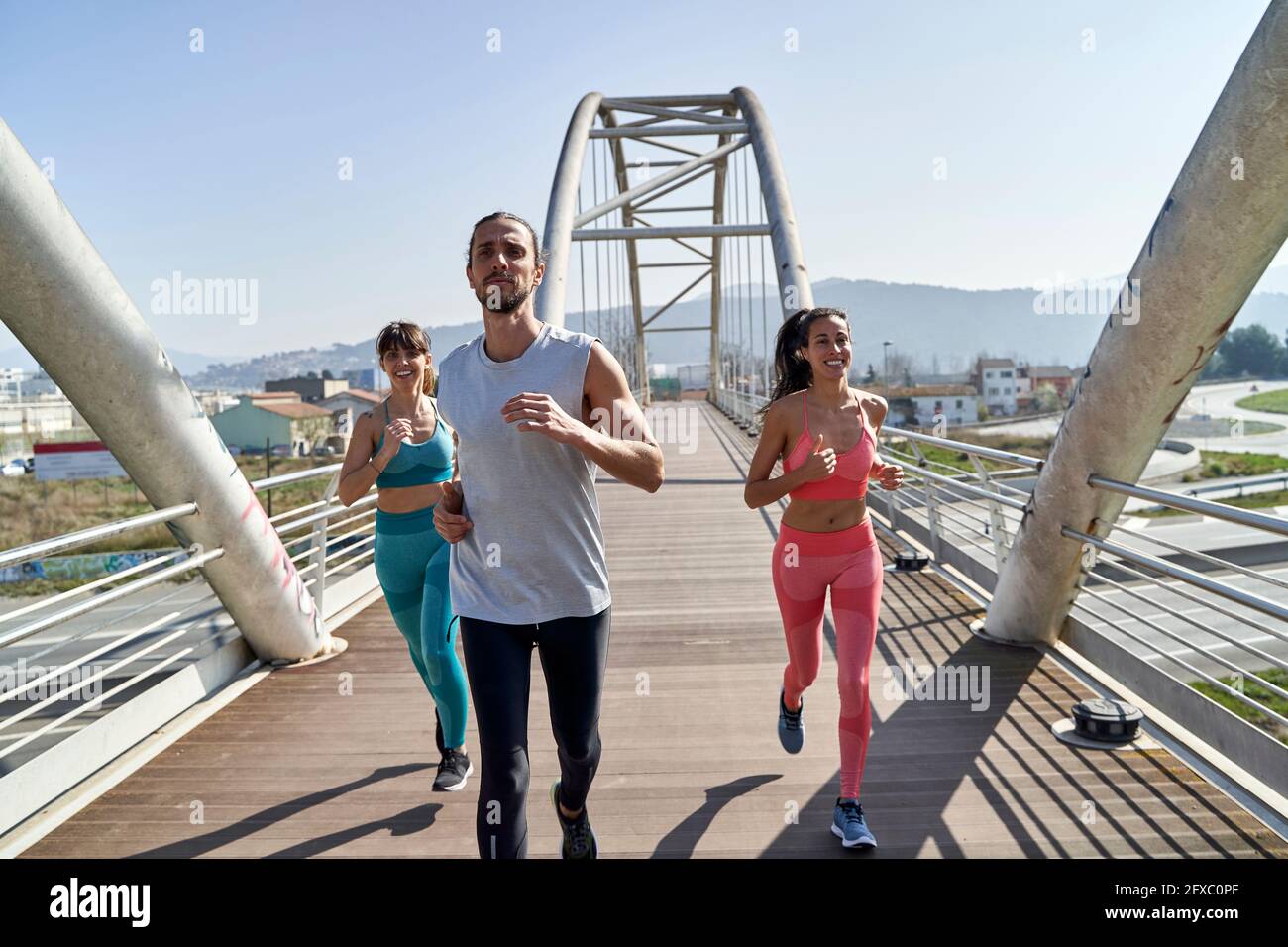 Amici multietnici consapevoli della salute che corrono sul ponte Foto Stock