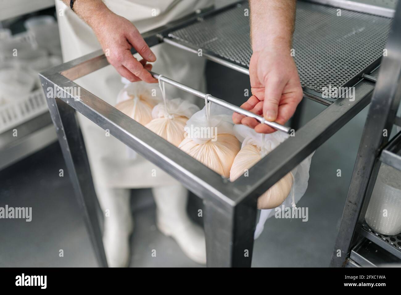 Lo chef tiene la verga di formaggio appeso avvolto in abiti presso la fabbrica Foto Stock