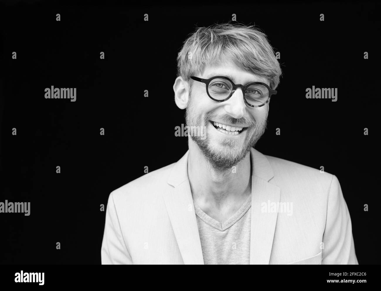 Uomo felice che indossa occhiali su sfondo nero Foto Stock