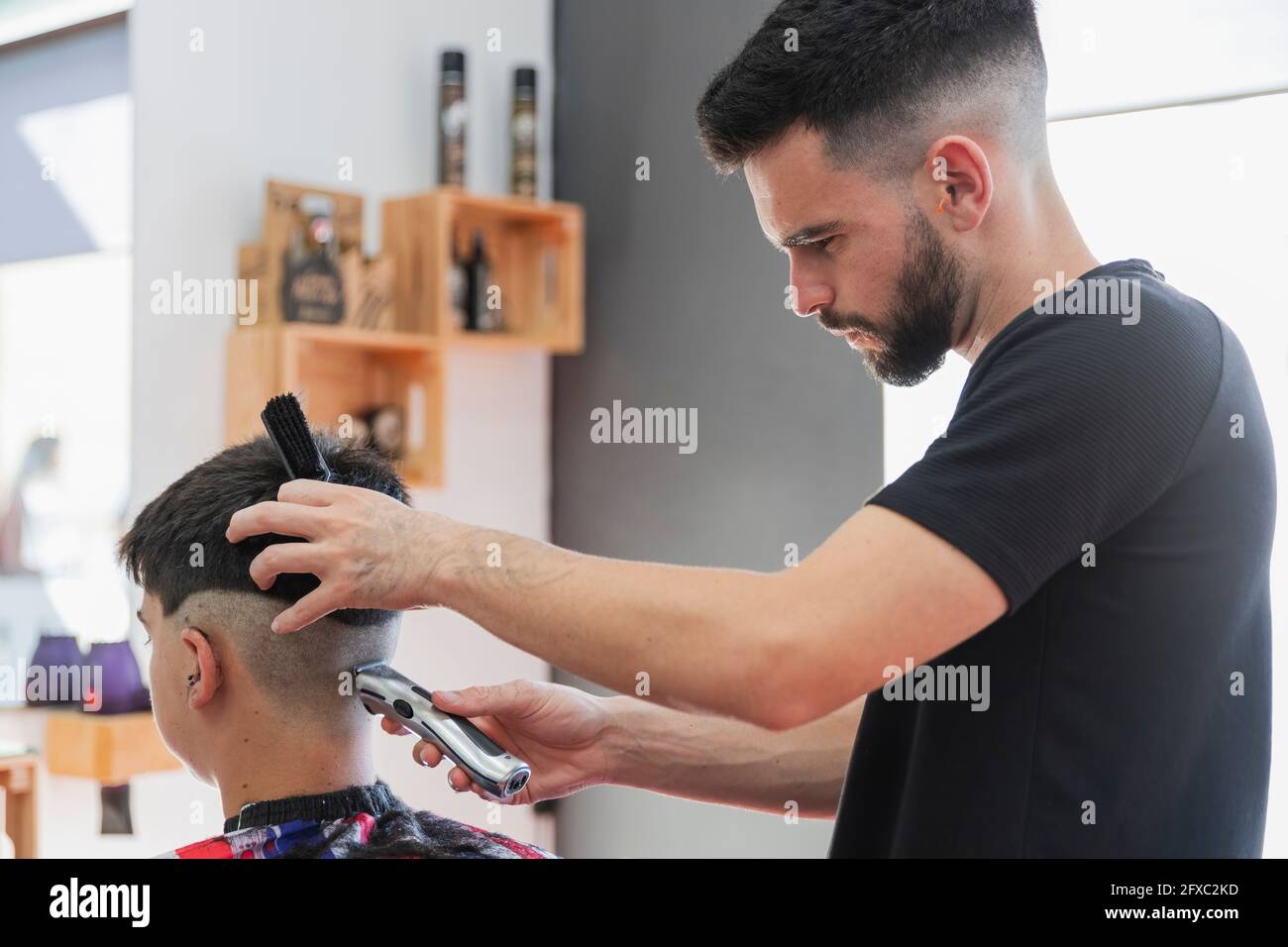 Barbiere maschile utilizzando la macchina per tagliare i capelli del  ragazzo adolescente al salone Foto stock - Alamy