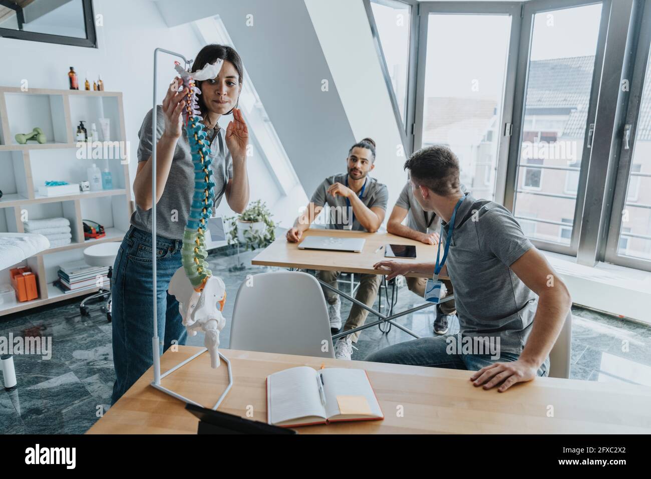 Allenatore femminile che guarda il modello della colonna vertebrale durante l'allenamento in classe Foto Stock