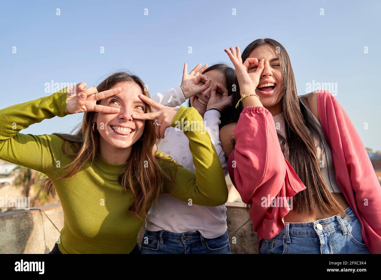 Divertenti amici femminili che fanno i volti mentre si godono sulla terrazza Foto Stock