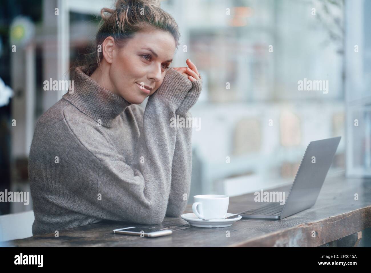 Un uomo d'affari medio adulto che si prende in considerazione mentre si siede accanto alla finestra del caffè Foto Stock
