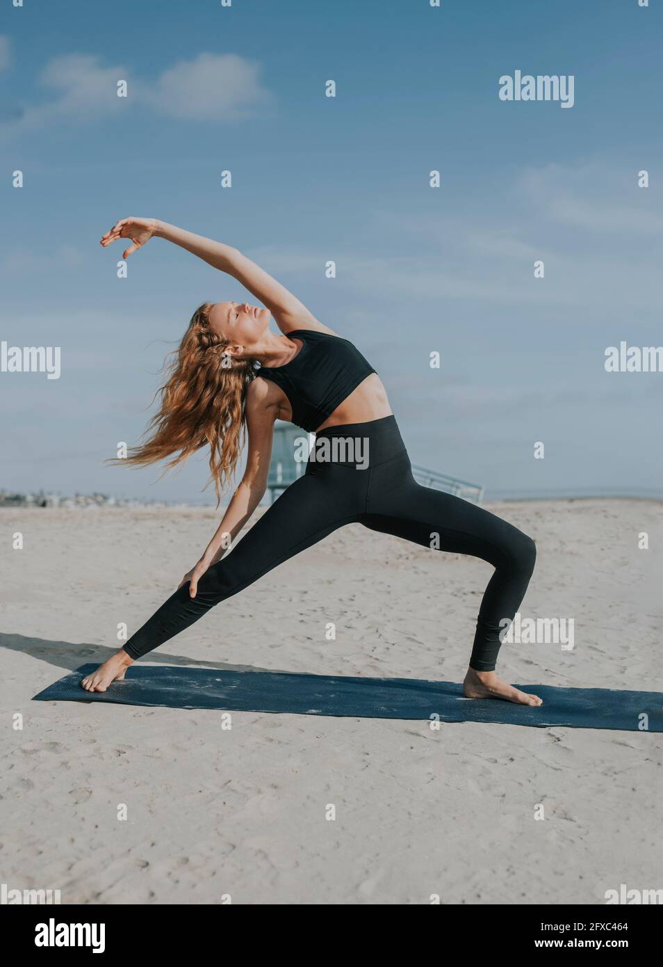 Giovane donna che stretching esercizio in spiaggia Foto Stock