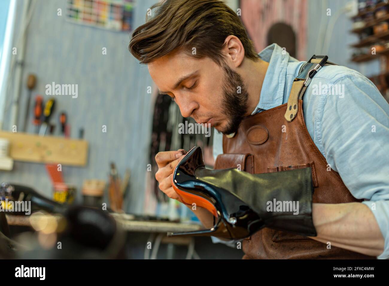 Pattino di incollaggio cobbler maschio in officina Foto Stock