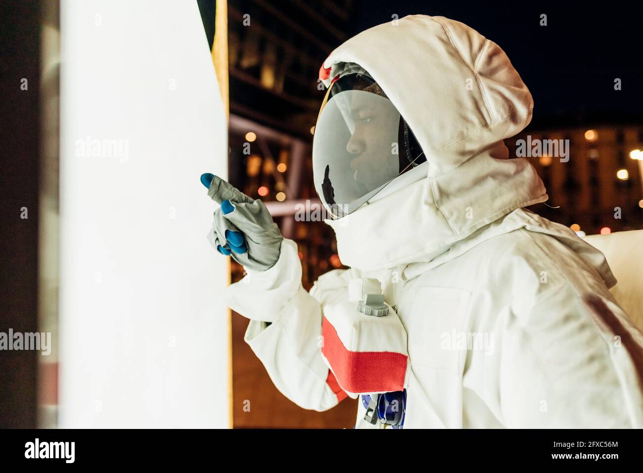 Astronauta maschile che punta sulla parete illuminata Foto Stock