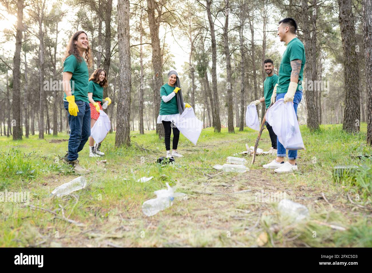 Ambientalisti in piedi con rifiuti di plastica in foresta Foto Stock