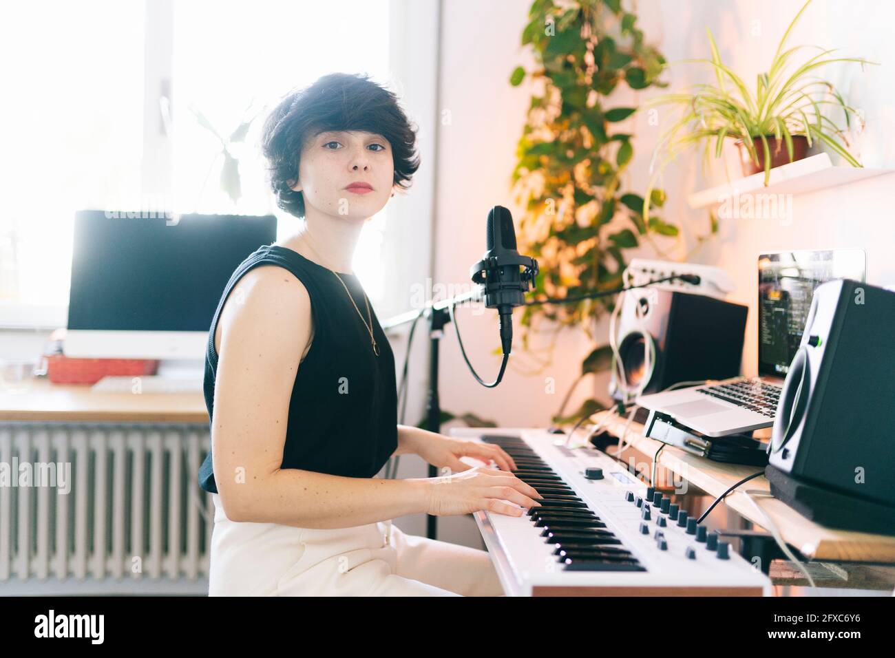 Compositore femminile che usa il pianoforte elettrico in studio Foto Stock