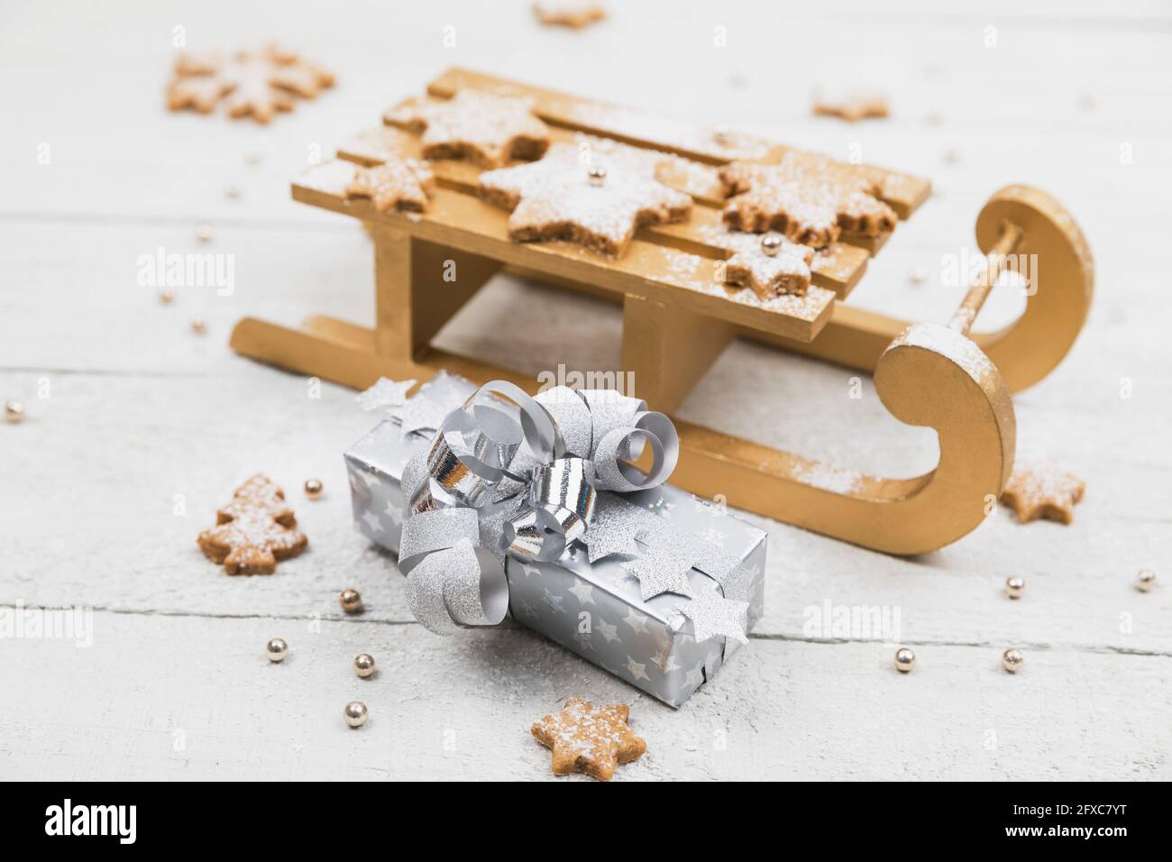 Regali di Natale e slitta con biscotti fatti in casa su sfondo di legno bianco Foto Stock