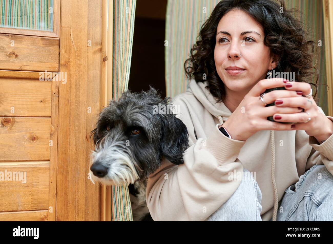 Donna e cane che guardano via mentre si siedono alla porta Foto Stock