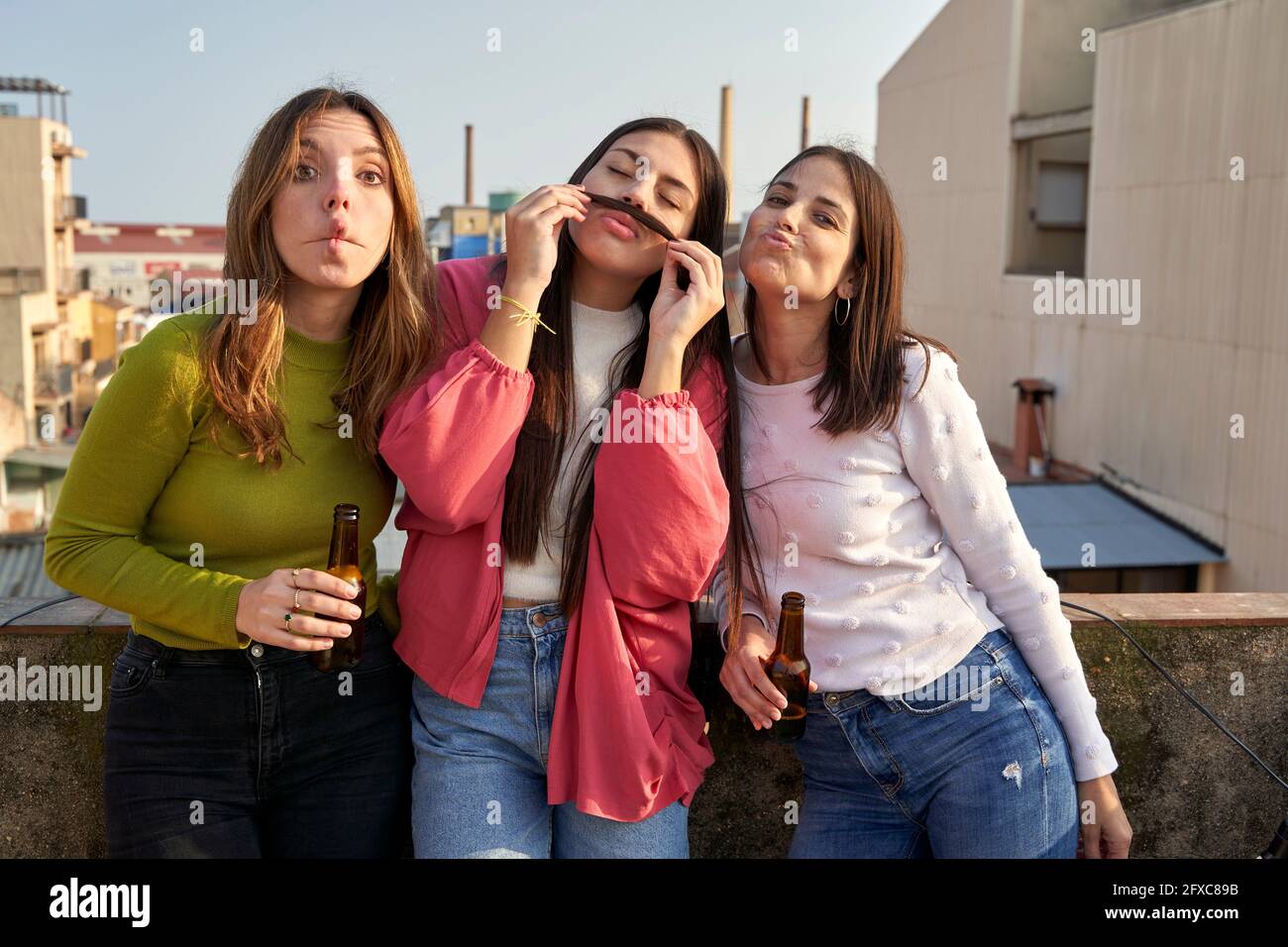 Amici maliziosi che fanno i volti mentre si levano in piedi sul tetto Foto Stock