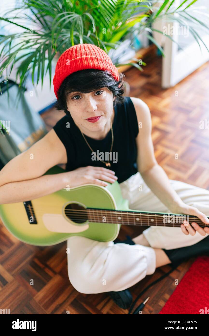 Musicista femminile seduto con la chitarra in studio Foto Stock