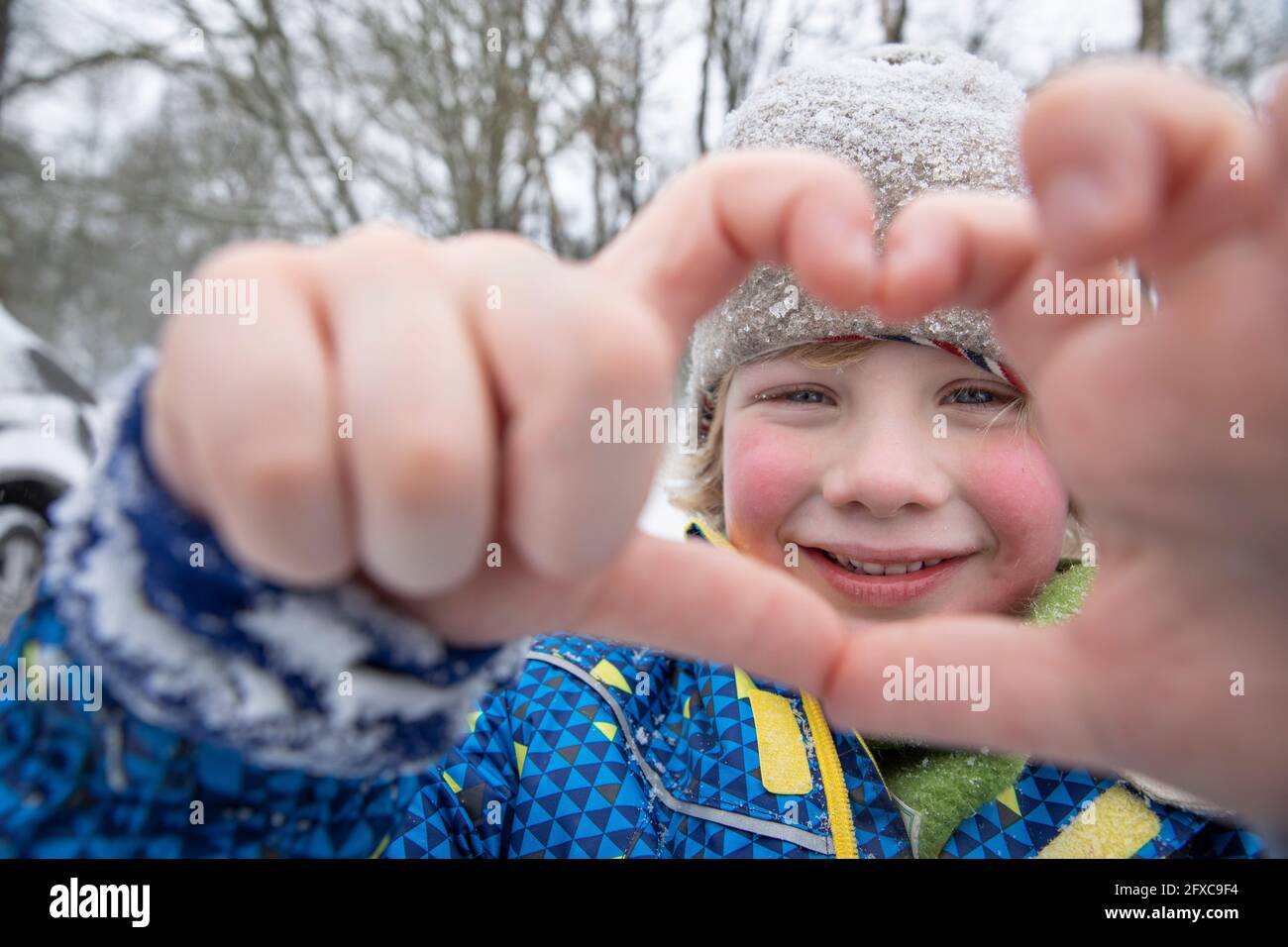 Ragazzo sorridente che gestiva con le mani durante l'inverno Foto Stock