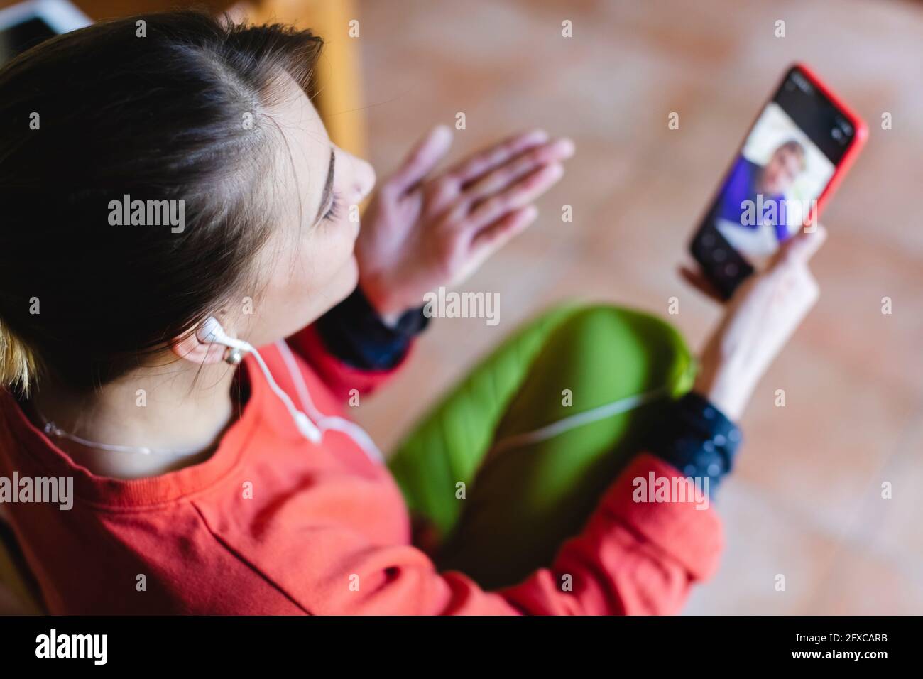 Donna che soffia un bacio durante la videochiamata su smartphone a casa Foto Stock