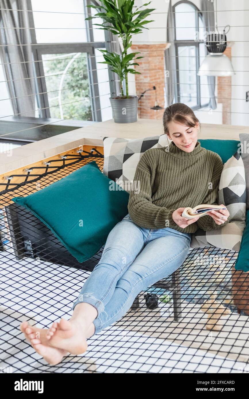 Donna che legge libro su amaca a casa Foto Stock