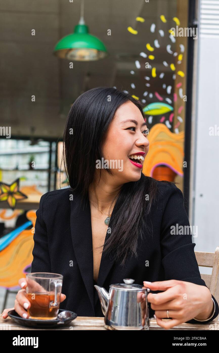 Giovane donna allegra al bar sul marciapiede Foto Stock