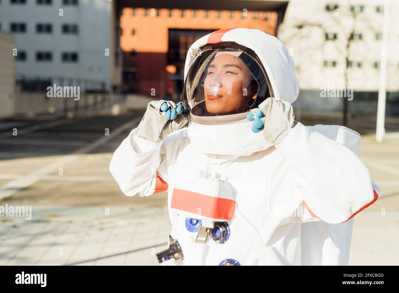 Astronauta femminile che tiene il casco mentre si sta in piedi all'aperto durante la giornata di sole Foto Stock