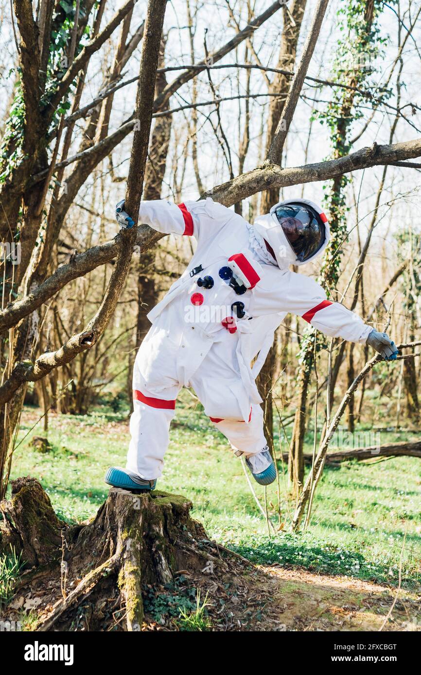 Astronauta femminile appeso al ramo dell'albero nella foresta Foto Stock
