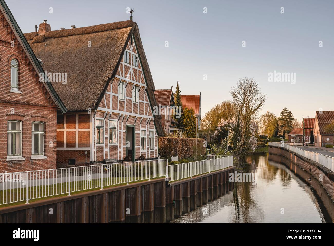 Germania, Altes Land, Jork, edificio a graticcio sul canale al tramonto Foto Stock