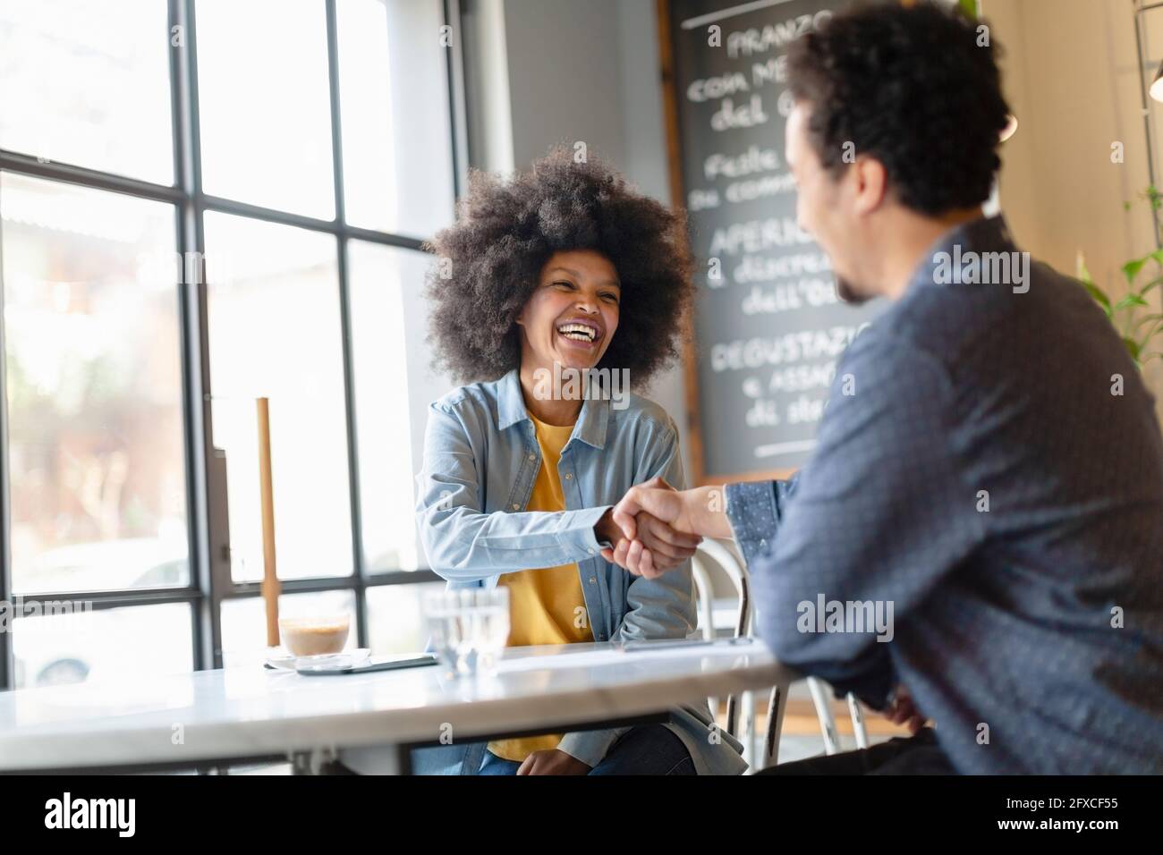 Cliente maschile che fa la stretta di mano con la donna d'affari dopo la riunione nel caffè Foto Stock