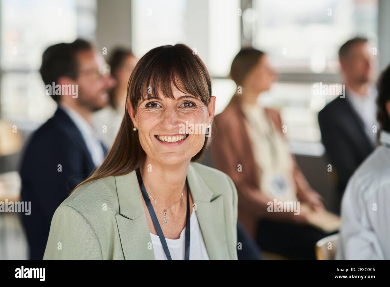 Sorridente imprenditore femminile con i colleghi all'evento educativo Foto Stock